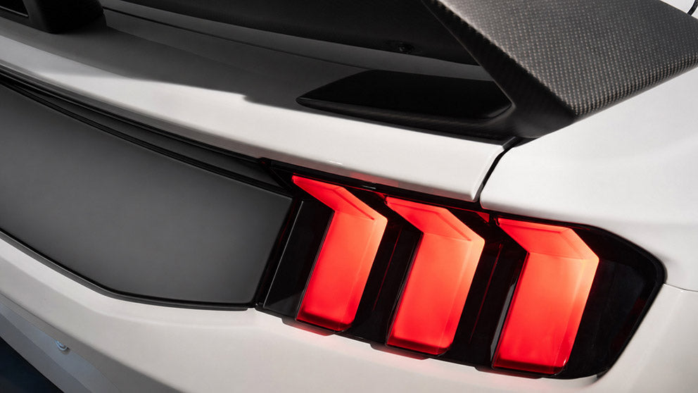 Close-up of 2024-27 Ford Mustang Stallion white tail lamps, LED tail lights by Ford Performance on a sleek vehicle.